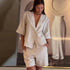 Woman wearing a beige linen outfit with a blurred background